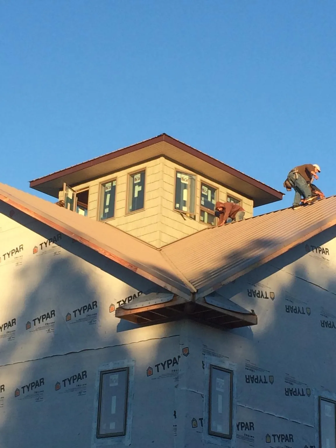Roofers working around a rooftop cupola on a new metal roof at sunset — Roof Waterproofing in Edgewater by Roofing Brothers